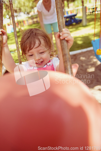 Image of mother and daughter swinging in the park