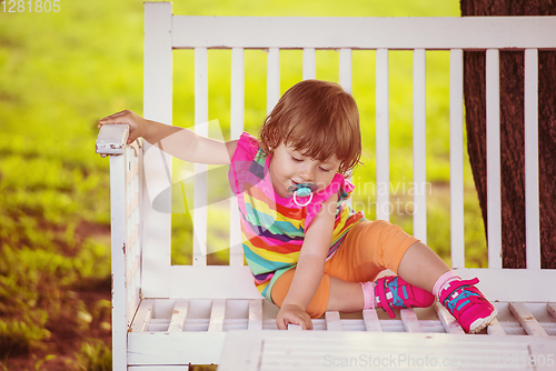 Image of cute little girl sitting on wooden bench