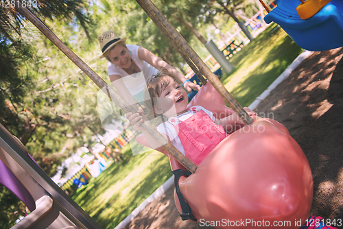 Image of mother and daughter swinging in the park