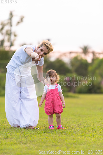 Image of mother and little daughter playing at backyard