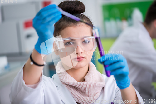 Image of female student with protective glasses making chemistry experime