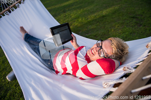 Image of woman using a tablet computer while relaxing on hammock