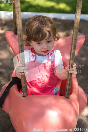 Image of little girl swinging  on a playground