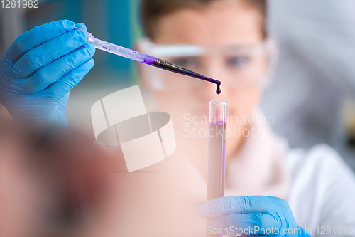 Image of female student with protective glasses making chemistry experime