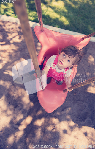 Image of little girl swinging  on a playground