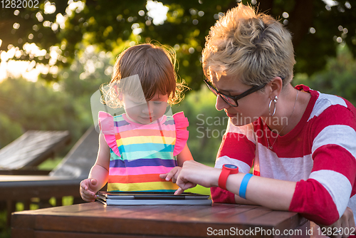 Image of mom and her little daughter using tablet computer