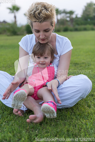 Image of mother and little daughter playing at backyard