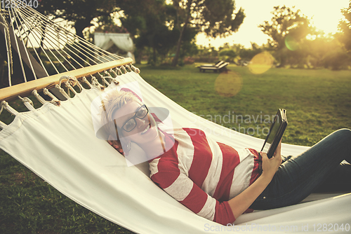 Image of woman using a tablet computer while relaxing on hammock