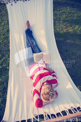 Image of woman reading a book while relaxing on hammock