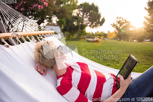 Image of woman using a tablet computer while relaxing on hammock