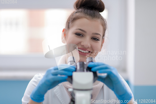 Image of female student scientist looking through a microscope