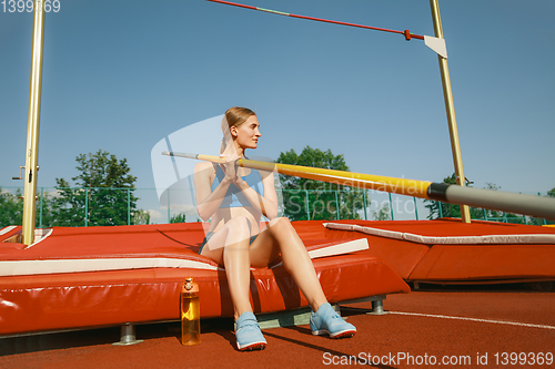 Image of Female high jumper training at the stadium in sunny day