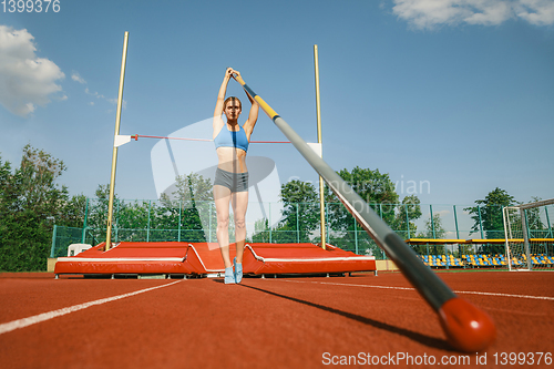 Image of Female high jumper training at the stadium in sunny day