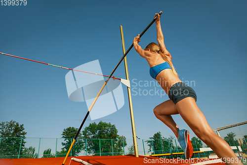 Image of Female high jumper training at the stadium in sunny day