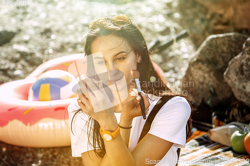 Image of Young couple having picnic at riverside in sunny day