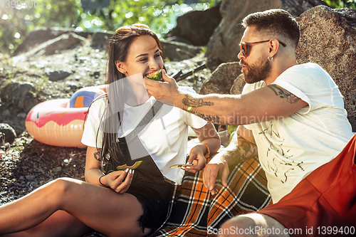 Image of Young couple having picnic at riverside in sunny day