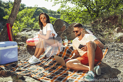 Image of Young couple having picnic at riverside in sunny day