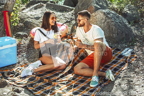 Image of Young couple having picnic at riverside in sunny day