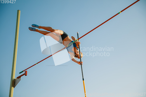 Image of Female high jumper training at the stadium in sunny day