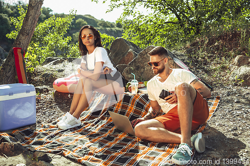 Image of Young couple having picnic at riverside in sunny day