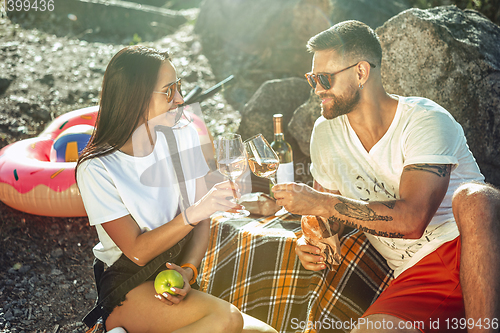 Image of Young couple having picnic at riverside in sunny day