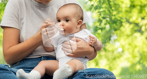 Image of close up of mother with spoon feeding little baby