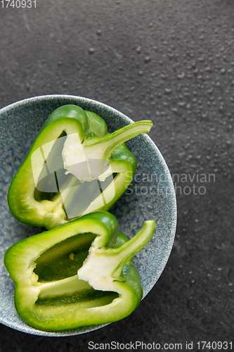 Image of cut green pepper in bowl on slate stone background