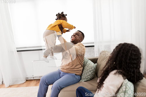 Image of african father playing with baby daughter at home