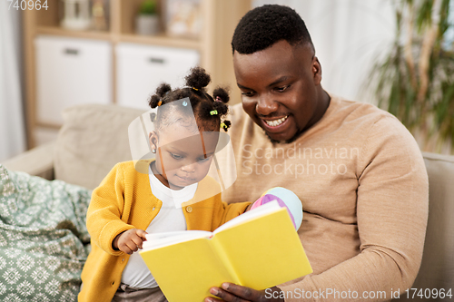 Image of african father reading book for baby daughter