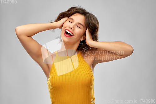 Image of happy laughing young woman in mustard yellow top