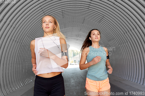 Image of young women with earphones and smartphones running