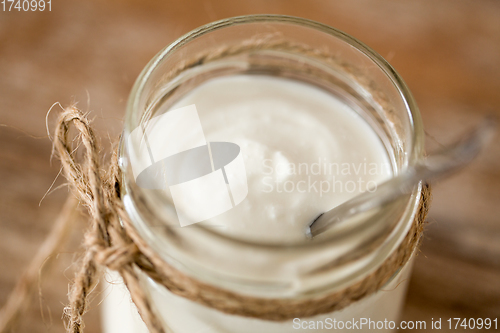 Image of yogurt or sour cream in glass jar on wooden table