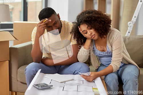 Image of sad couple with blueprint counting money at home