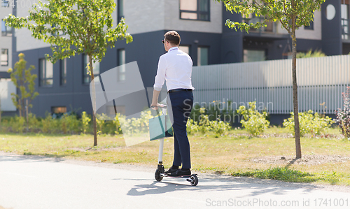 Image of businessman with shopping bag riding scooter