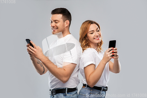 Image of happy couple in white t-shirts with smartphones