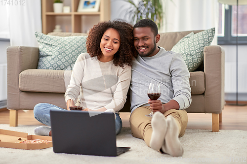 Image of happy couple with laptop drinking red wine at home