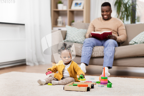 Image of african baby girl playing with toy blocks at home