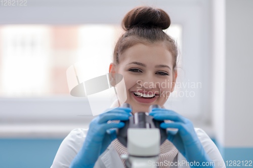 Image of female student scientist looking through a microscope