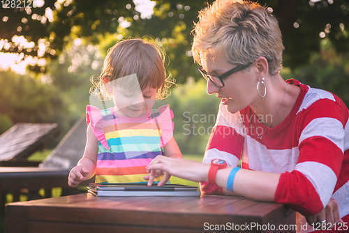 Image of mom and her little daughter using tablet computer