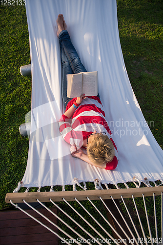 Image of woman reading a book while relaxing on hammock