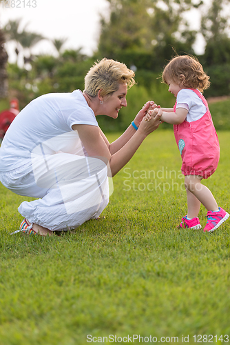 Image of mother and little daughter playing at backyard