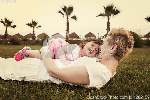 Image of mother and little daughter playing at backyard