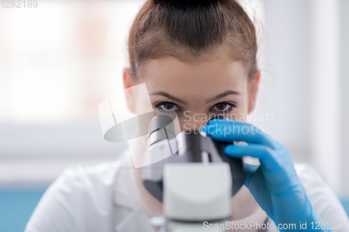 Image of female student scientist looking through a microscope