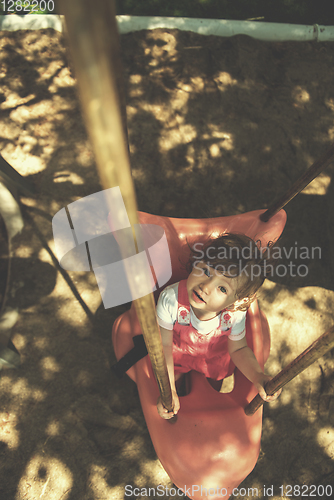 Image of little girl swinging  on a playground