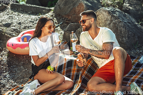 Image of Young couple having picnic at riverside in sunny day