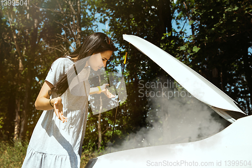 Image of Young woman traveling on the car in sunny day