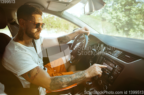 Image of Young man preparing for vacation trip on the car in sunny day