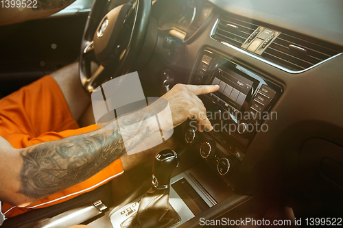 Image of Young man preparing for vacation trip on the car in sunny day