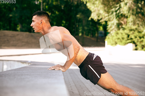 Image of A male athlete doing workout on the city\'s street or park