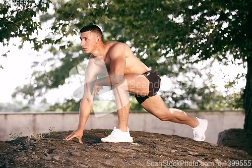Image of A male athlete doing workout on the city\'s street or park